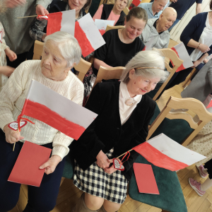 Na zdjęciu widać Mieszkańców Domu Pomocy Społecznej Pracownika Oświaty wraz z otrzymanymi, ręcznie malowanymi flagami podarowanymi przez Dzieci z Przedszkola nr 42 w Warszawie.