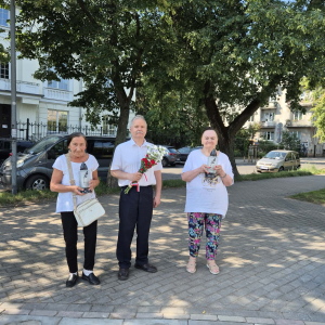 Mieszkańcy DPS Pracownika Oświaty przed pomnikiem i złożeniem kwiatów i zapaleniem zniczy