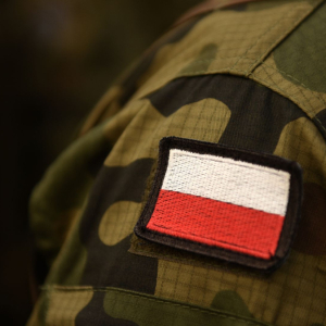 Zdjęcie przedstawia fragment munduru żolnierza z biało-czerwoną naszywką